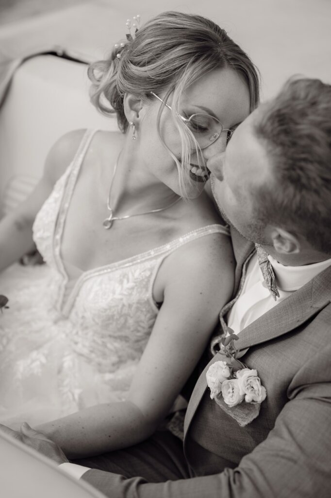 Brautpaar sitzt im Auto und es küsst sich liebevoll Schwarz weiss