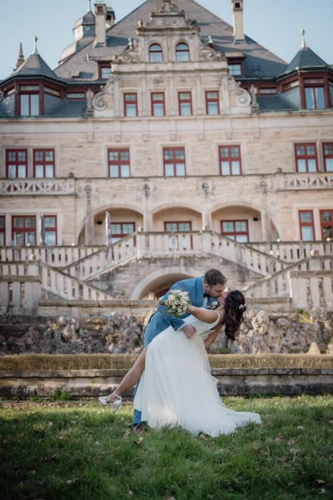 Brautpaar vor dem Schloss Wolfsbrunnen, der Bräutigam küsst seine Braut sehr romantisch