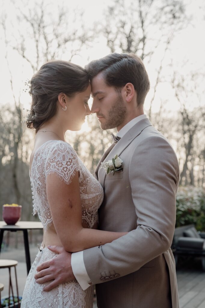 Brautpaar steht auf einer Terrasse Stirn an Stirn und die Sonne schein